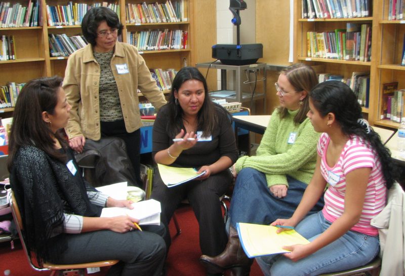 Group of women sitting in a circle in a library, deep in conversation.