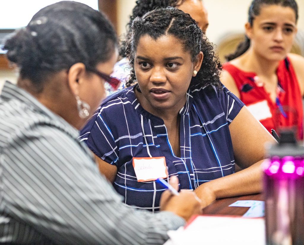 Two women in deep conversation with others blurred out in the background.