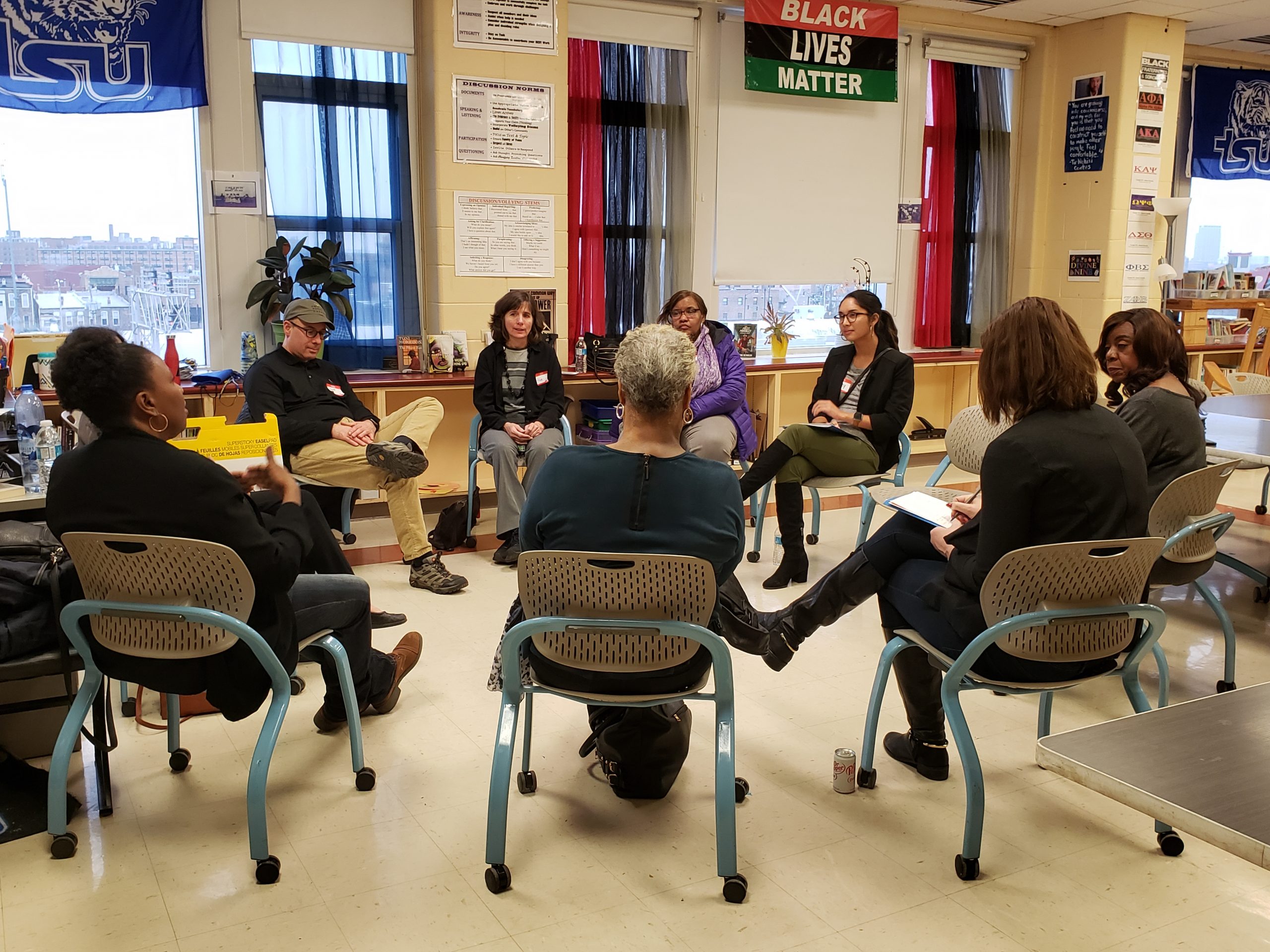 Group of adults seated in a circle in a classroom, in conversation